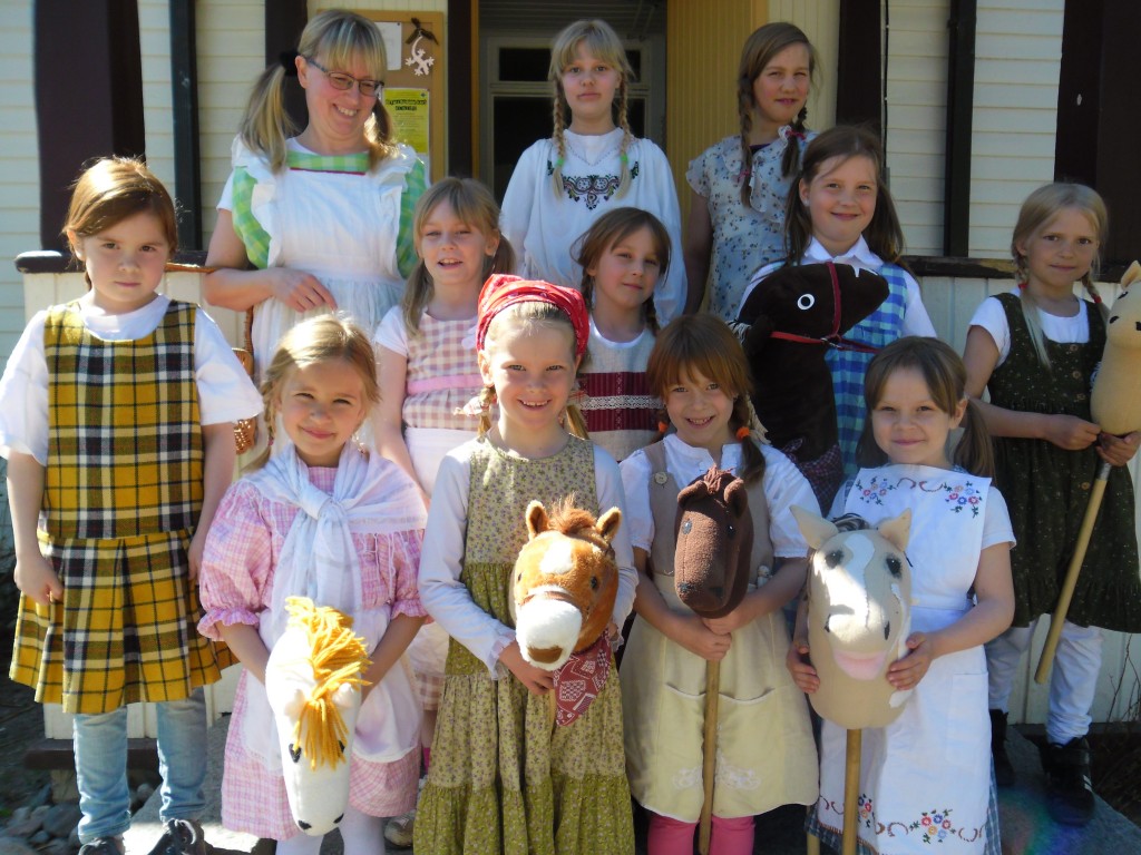 Kankaisten koululaiset varustautuivat toukosiunaukseen kesäisin asuin ja sopivin varustein. Heitä ohjasi kankaisten kylälle opettaja Päivi Minkkinen. Kuvassa oppilaat ovat lähtötunnelmissa kotoisen koulunsa rappusilla. (kuva: Taina Hoskari)